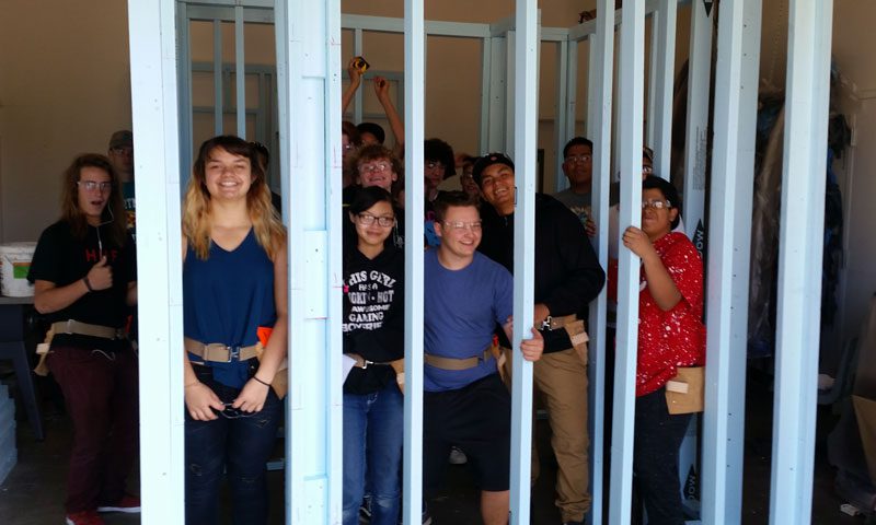 A wide shot of Build Pagosa Students inside a drywall frame project that they built